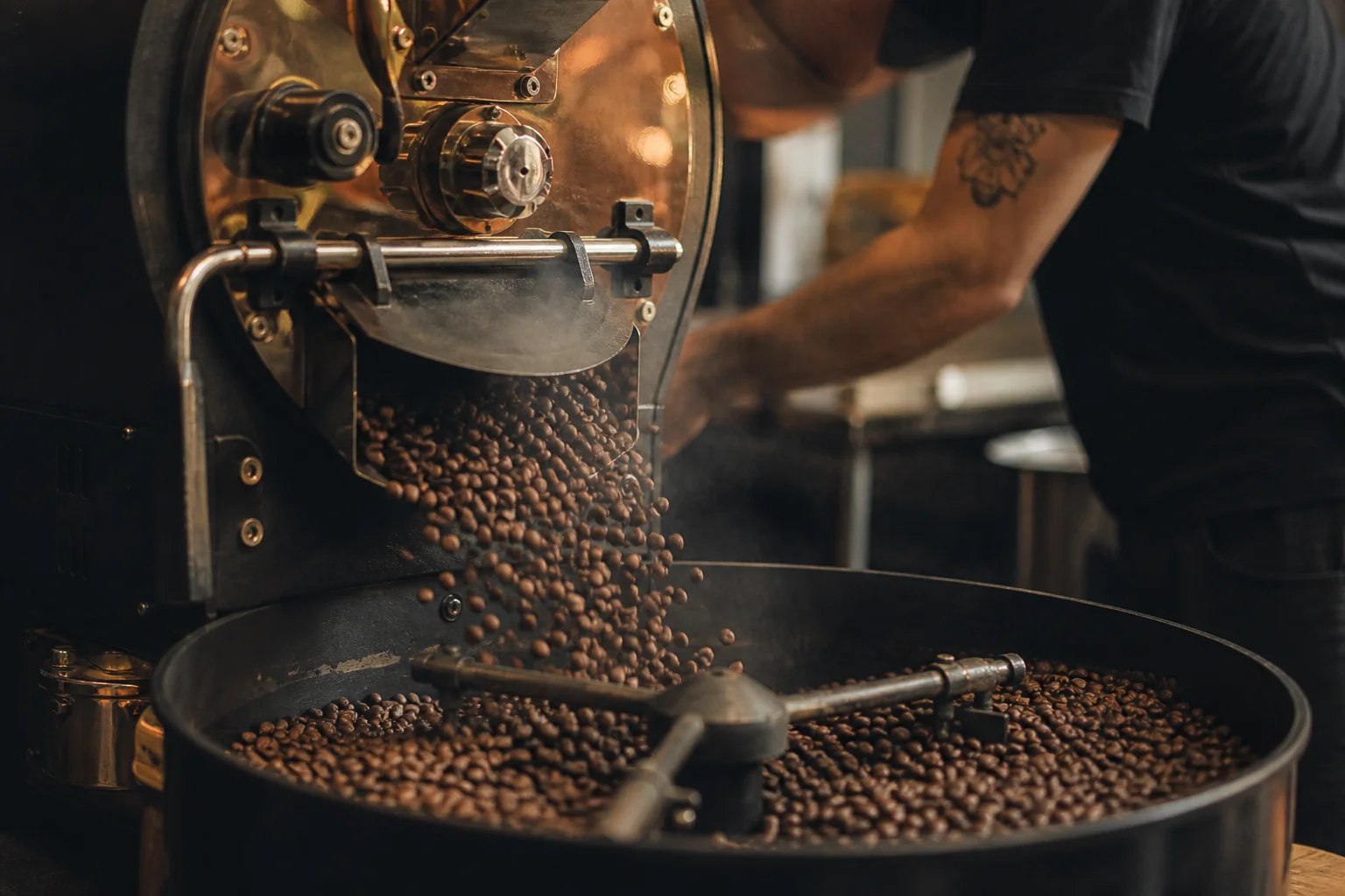 Fresh coffee beans falling from a small drum roaster